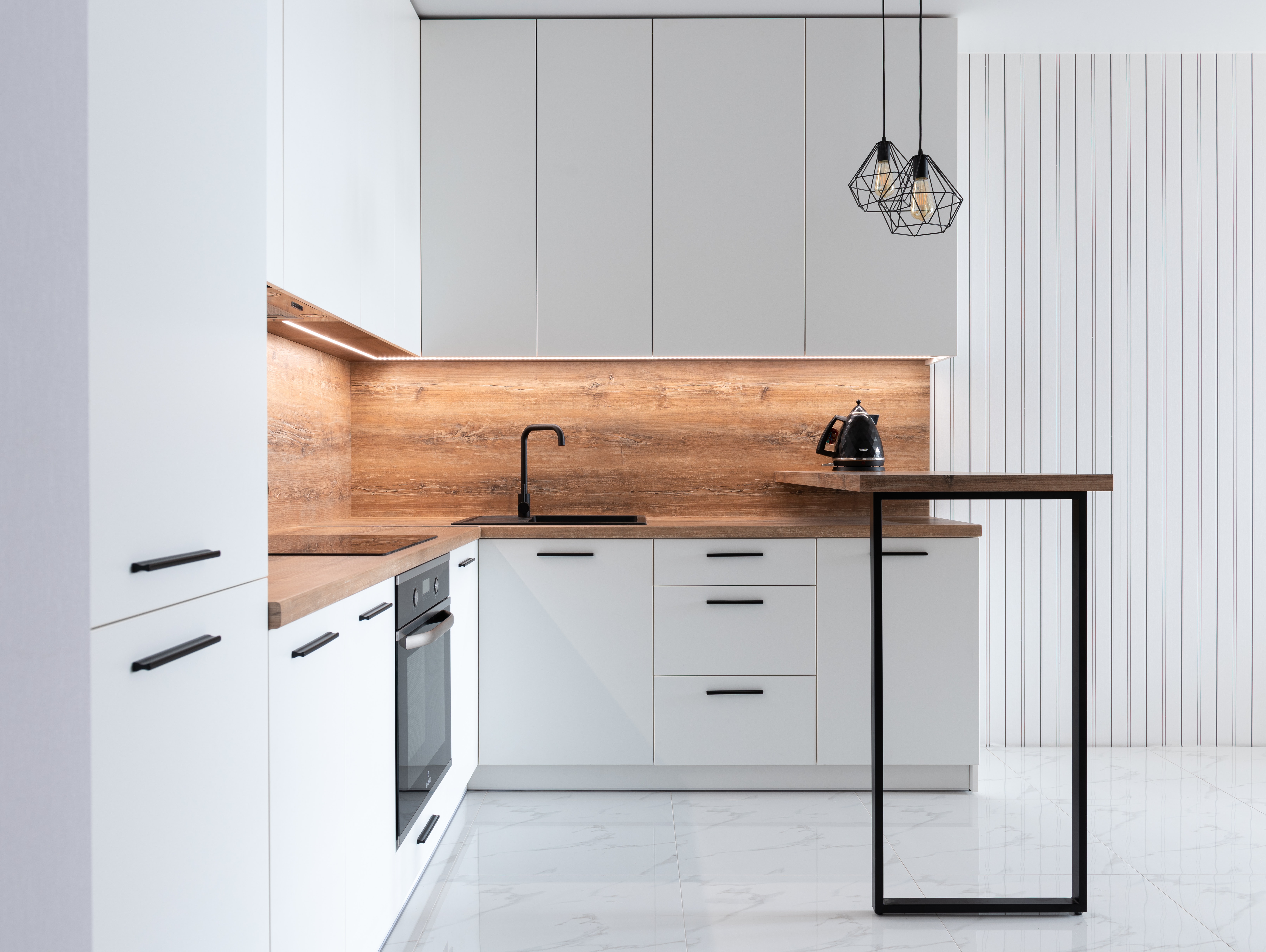 Stock Photo featuring white-washed kitchen design and warm-toned wooden backsplash